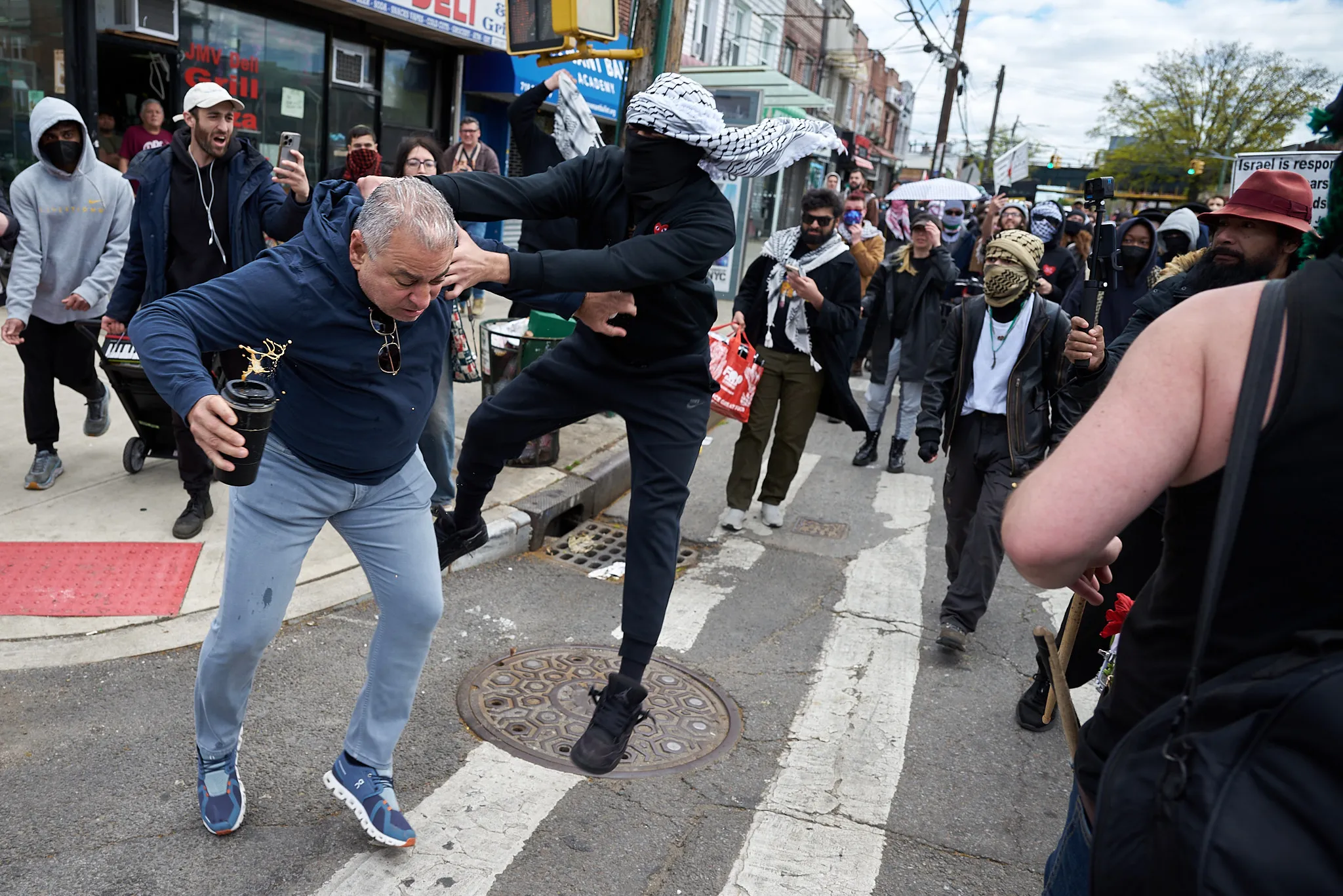 Another protestor wearing a keffiyeh jumps the coffee spiller