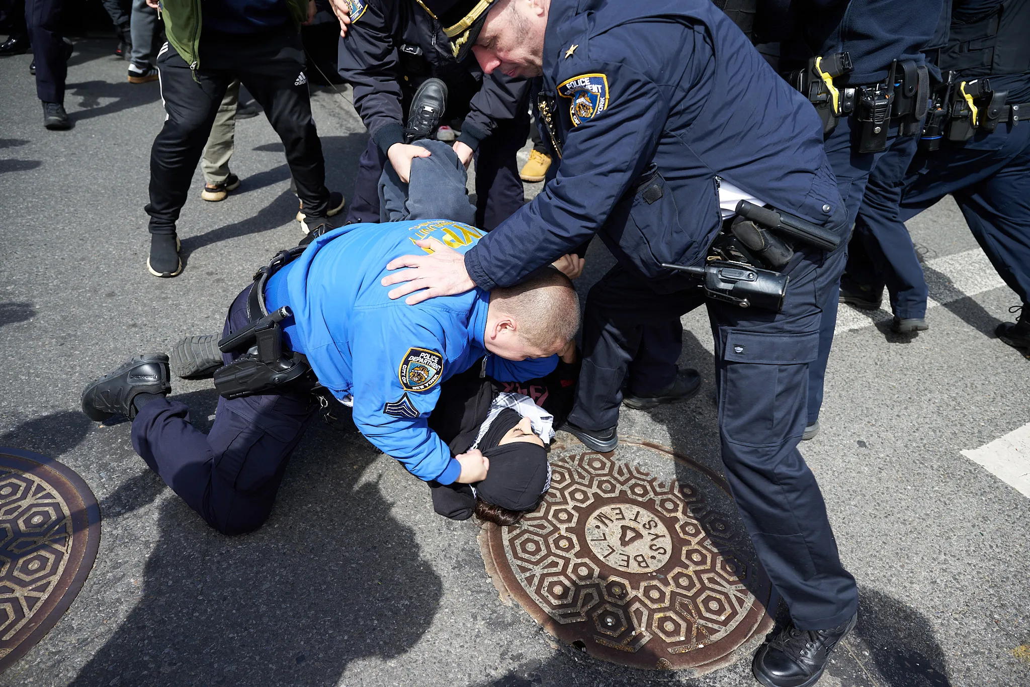 Multiple NYPD officers pin down a protestor to arrest them