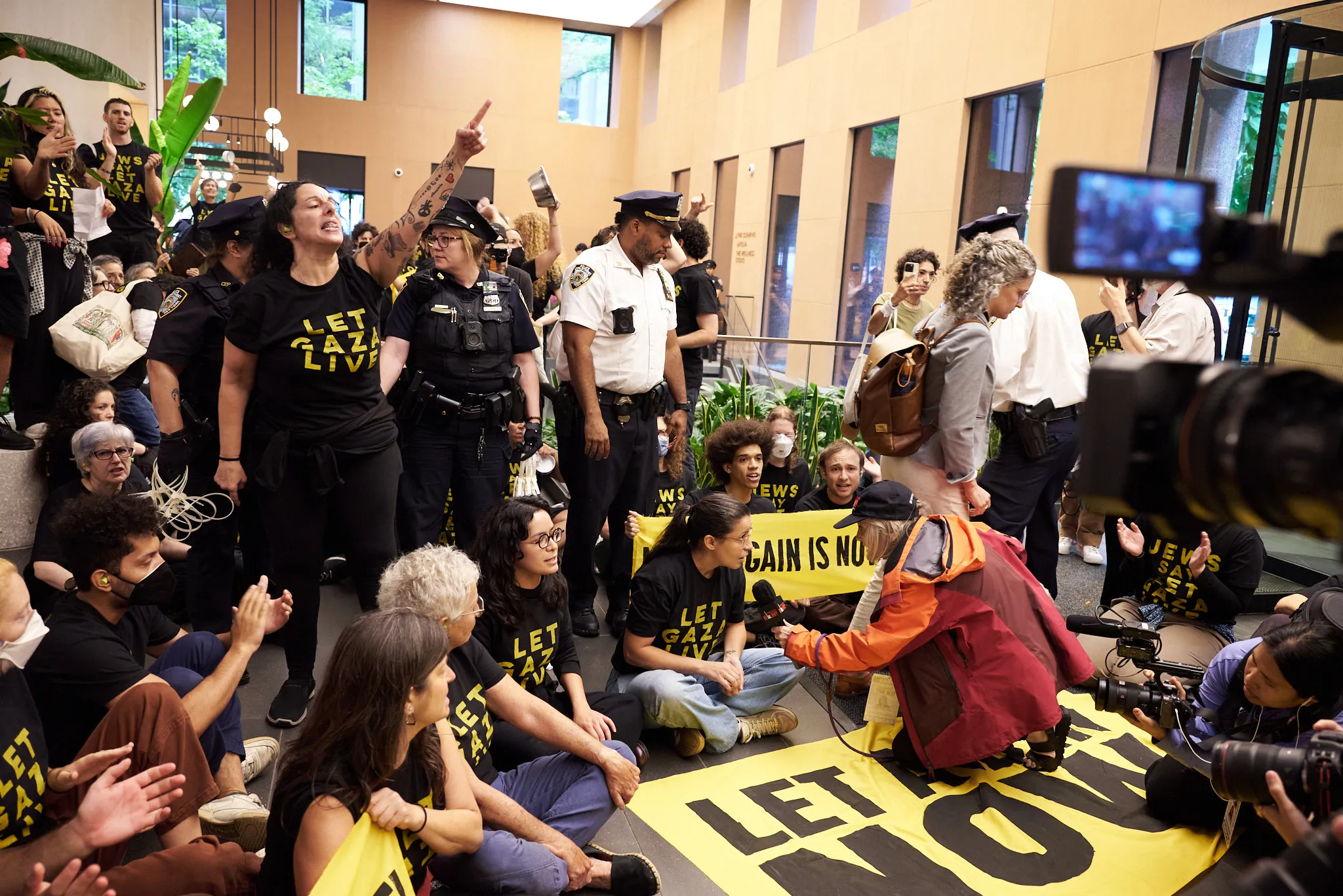 Protestors in building lobby as Amy Goodman conducts an interview and police officers begin arrets