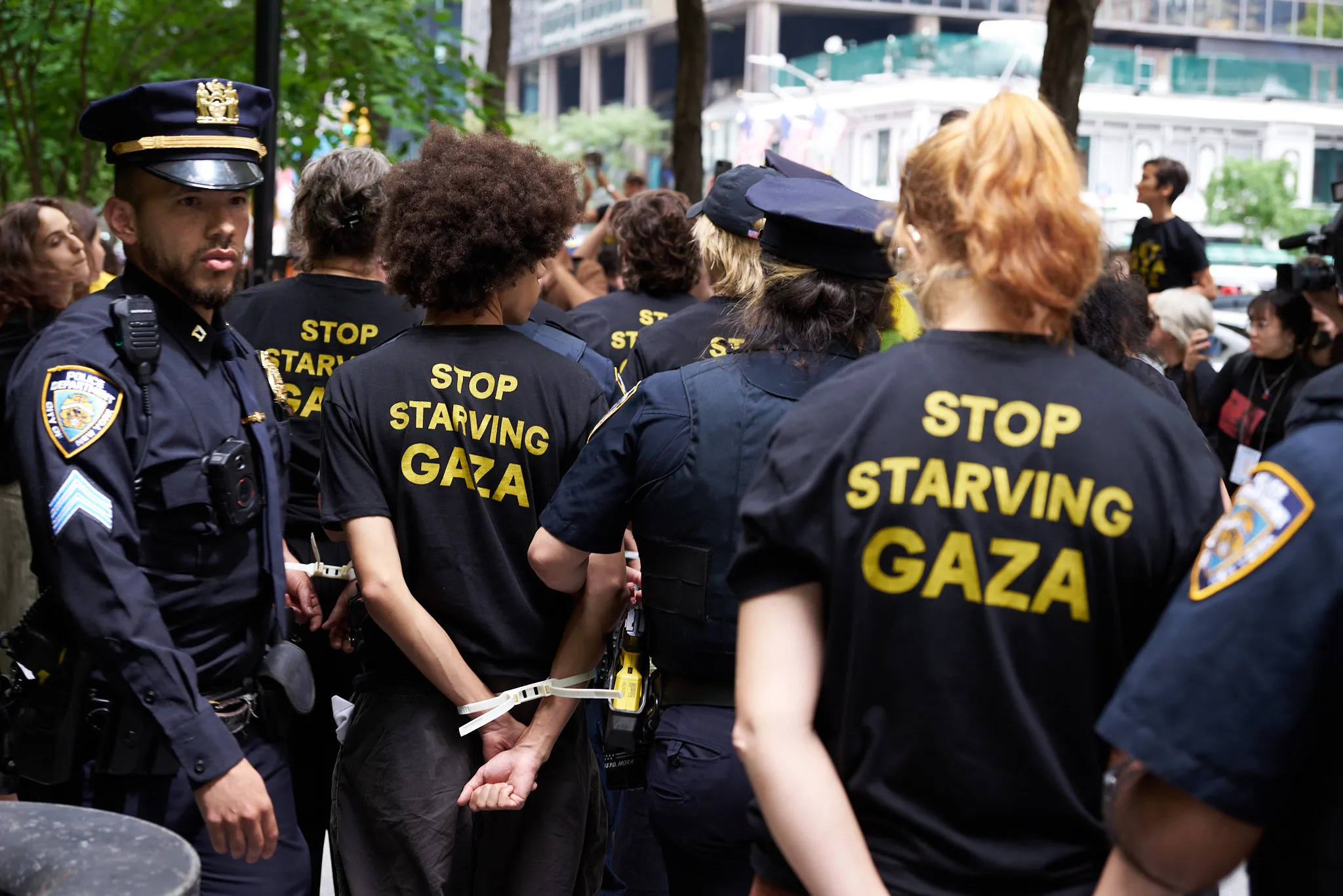 Line of protestors with being led away hands zip-tied behind their backs